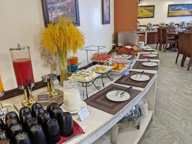 The breakfast buffet area with drinks, fresh fruit, and cooked dishes at Sapa Relax Hotel