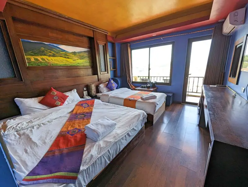 A queen size bed and twin size bed with colorful pillows and bedrunner and blue walls at Saparis Hotel in Sapa, Vietnam
