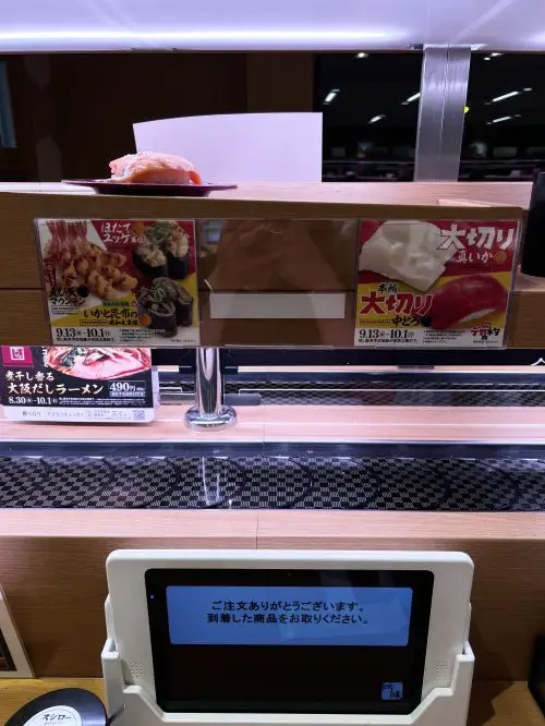 A red sushi plate getting delivered on a special conveyor belt at Sushiro restaurant