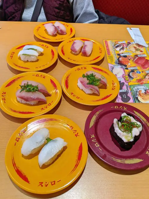 Six yellow plates and 1 dark red plate of sushi at Sushiro, a conveyor belt sushi restaurant