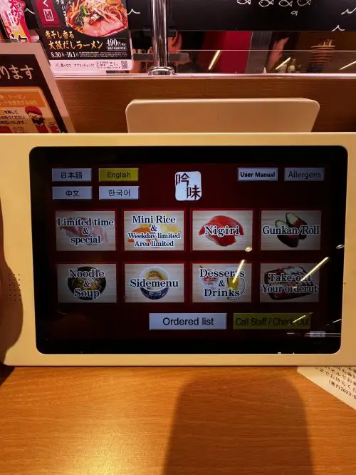 A tablet showing the menu options such as specials, nigiri, rolls, noodles, side dishes, and more in English