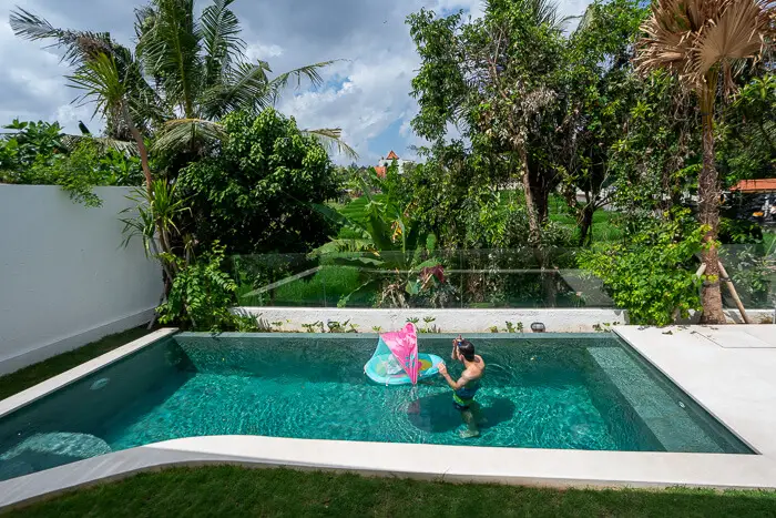 A man with a baby in a baby swimming float at a pool in Bali