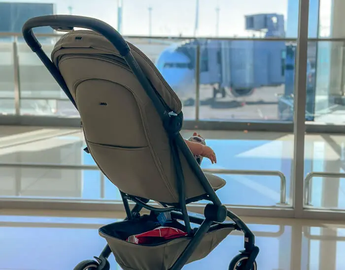 A baby sits inside a stroller waiting for his flight at the airport