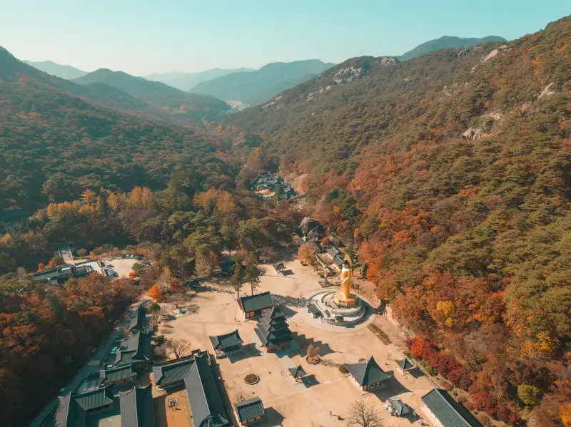 An aerial view of Beopjusa Temple and a Buddha statue and the fall leaves at Songnisan National Park, South Korea