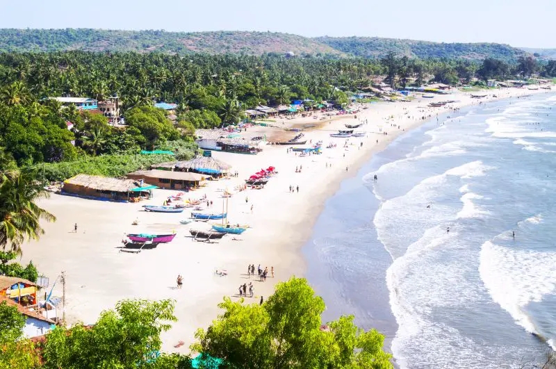 A view of people and boats on the white sandy beach of Arambol Beach in Goa, India, one of the best alternative places to visit instead of Bali, Indonesia