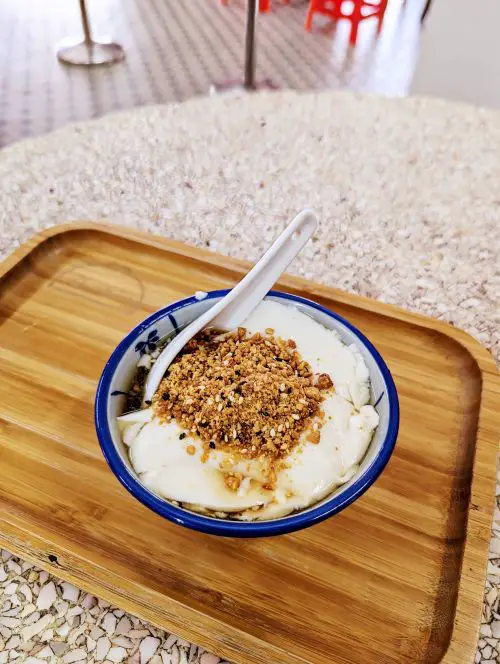 A bowl of tau fu fa soft tofu dessert with peanuts and sesame at Big Mom Beancurd in Ipoh, Malaysia