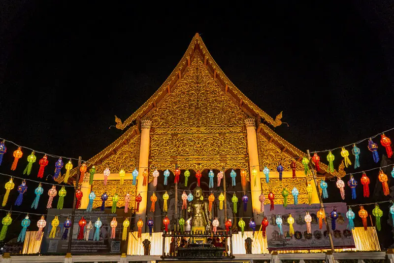 An evening view of a golden temple in Chiang Mai with colorful lanterns lit