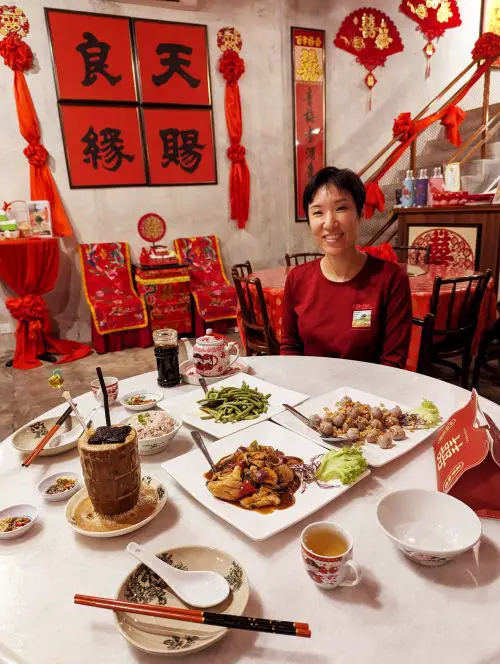 Jackie Szeto, Life Of Dooing, sits at the table with Hakka foods at Hakka Restaurant Ipoh Town in Ipoh, Malaysia