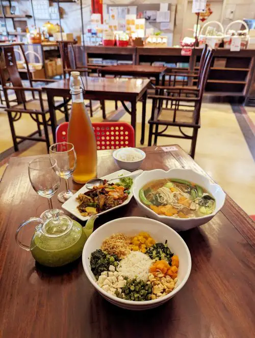 A table with lei cha rice, vegetarian bak kuh teh, mushroom and veggies, and a bottle of cold brew tea at Purple Cane Tea House in Ipoh