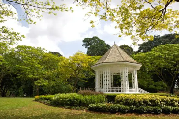 A white gazebo called the Bandstand surrounded by trees and grass at the Singapore Botanic Gardens
