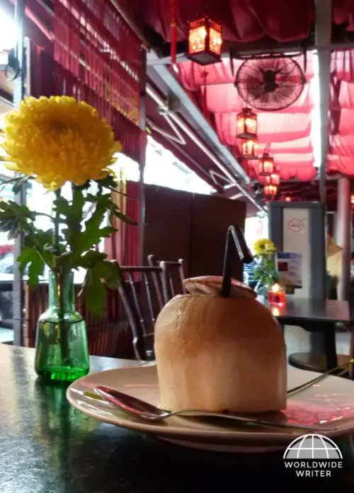 A young coconut served on a plate with a spoon at a cafe in Singapore Chinatown area
