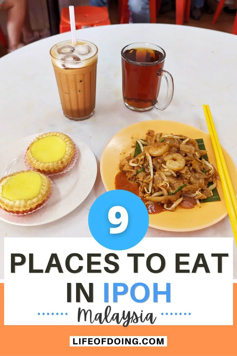 A coffee shop in Ipoh, Malaysia that has a plate of egg tarts, char kway teow fried noodles, iced coffee and hot tea