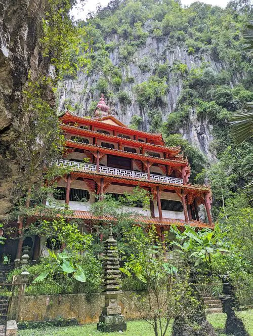 A red multi-story building next to Tortoise Pond at Sam Poh Tong Temple, Ipoh, Malaysia