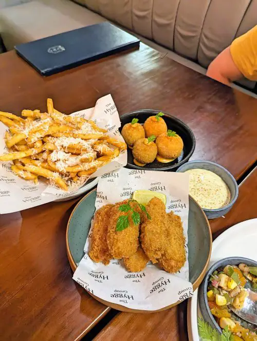 Four plates of small dishes at Hygge Dining and Bar in Penang's Georgetown area - fried oysters, truffle fries, mushroom croquette, and octopus salsa