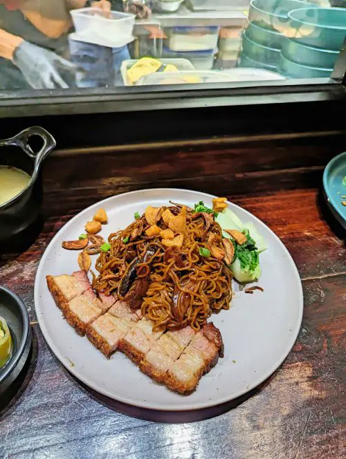 A plate of noodles with roasted pork and vegetables and topped with pork fat at Ichi Tong in Penang