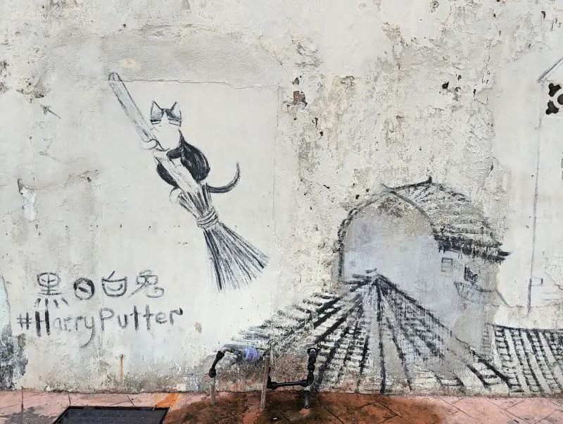 The Harry Putter artwork in Melaka of a black and white cat riding a broomstick and next to a railway