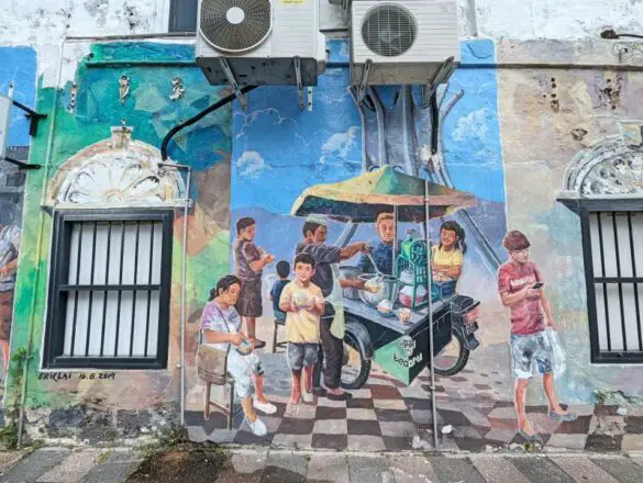 A street art in Ipoh of people enjoying a bowl of iced cendol dessert