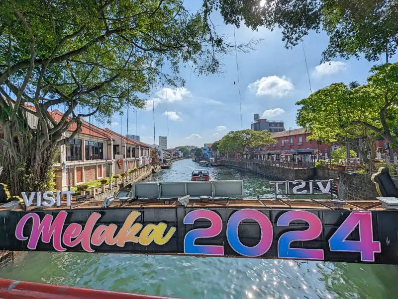 A Visit Melaka 2024 sign over the Melaka River