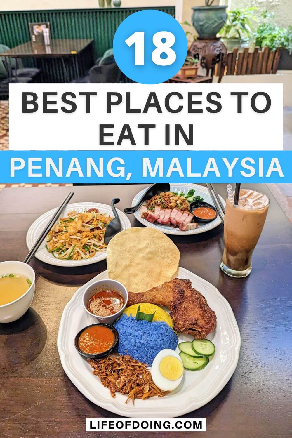 A table with traditional Malaysian food such as fried chicken with fried anchovies and yellow and blue rice, stir fry noodles, and noodles with roasted pork in one of the restaurants in Penang Georgetown