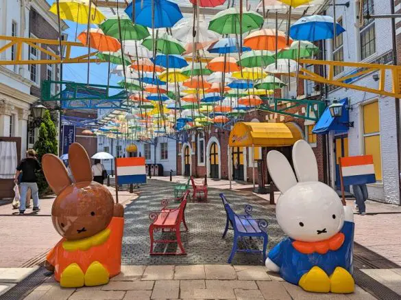Melanie, the brown bunny, and Miffy, the white bunny holds the Dutch flags and are under the Umbrella Street at Huis Ten Bosch in Nagasaki, Japan
