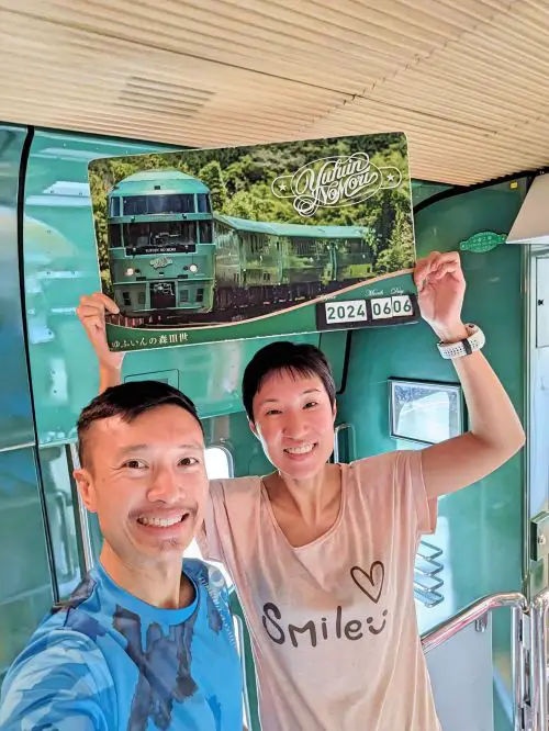 Justin Huynh and Jackie Szeto, Life Of Doing, take a photo with the Yufuin no Mori poster