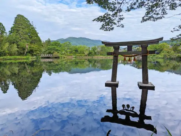 A grey torii with a reflection in the water, located in the middle of Kinrin Lake in Yufuin, Japan
