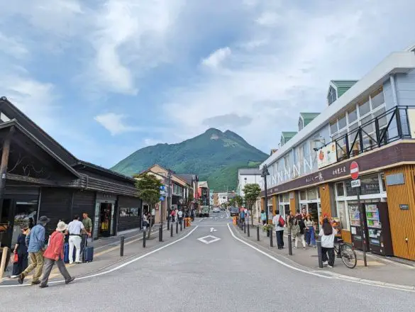People walking on the sidewalks and a green Mount Yufu mountain in the backdrop