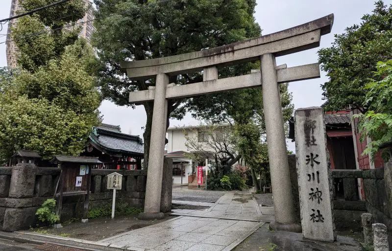 Front entrance of the Azabu Hikawa Shrine with the grey torii gate and shrine signage
