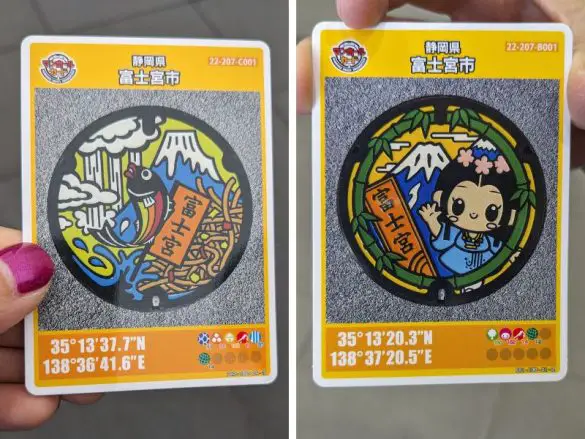 Japan-Manhole-Card-Featured-Photo Two manhole cover cards from Fujinomiya, Japan - one is a fish with Mount Fuji and the other is a princess and Mount Fuji