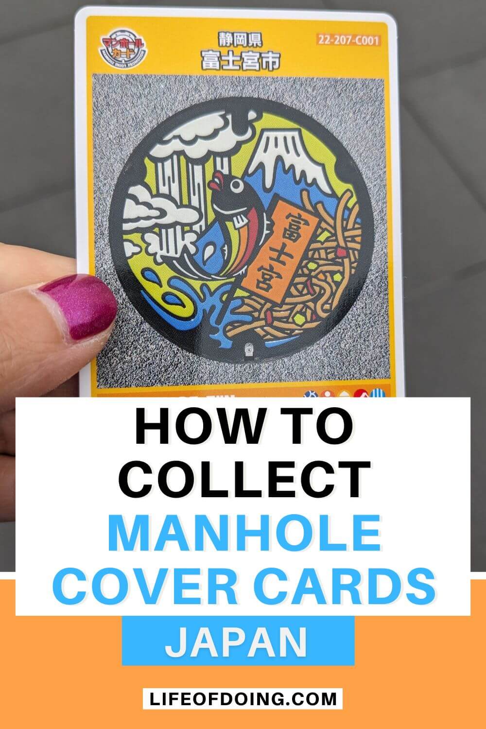 A hand holding one of the manhole cards from Fujinomiya of a fish and Mount Fuji