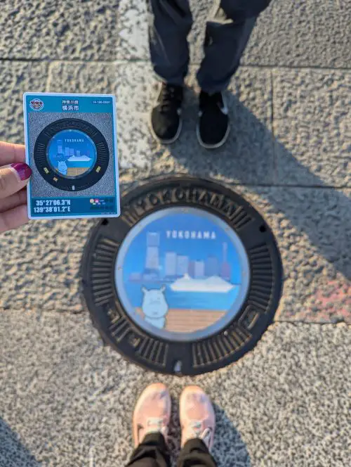 A hand holding a manhole card of a hippo in Yokohama