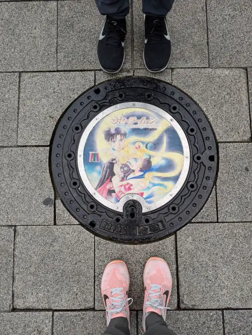 A manhole cover of Sailor Moon, Tuxedo Mask, and Luna the cat in Tokyo, Japan