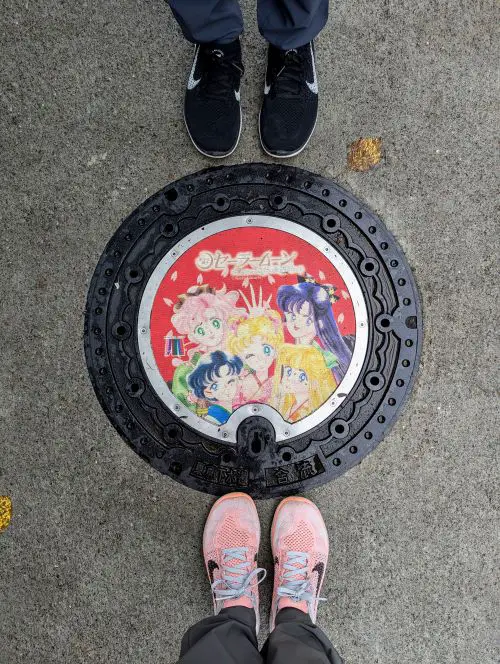 Life Of Doing stands around the red manhole cover of Sailor Moon and friends in Tokyo, Japan