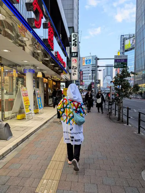 Jackie Szeto, Life Of Doing, wears the Tokyo Marathon finisher's poncho on the way to dinner