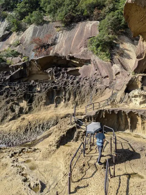 Justin Huynh, Life Of Doing, holds an umbrella to cover body from the sun while he walks along the Onigajo Cliffside walking path