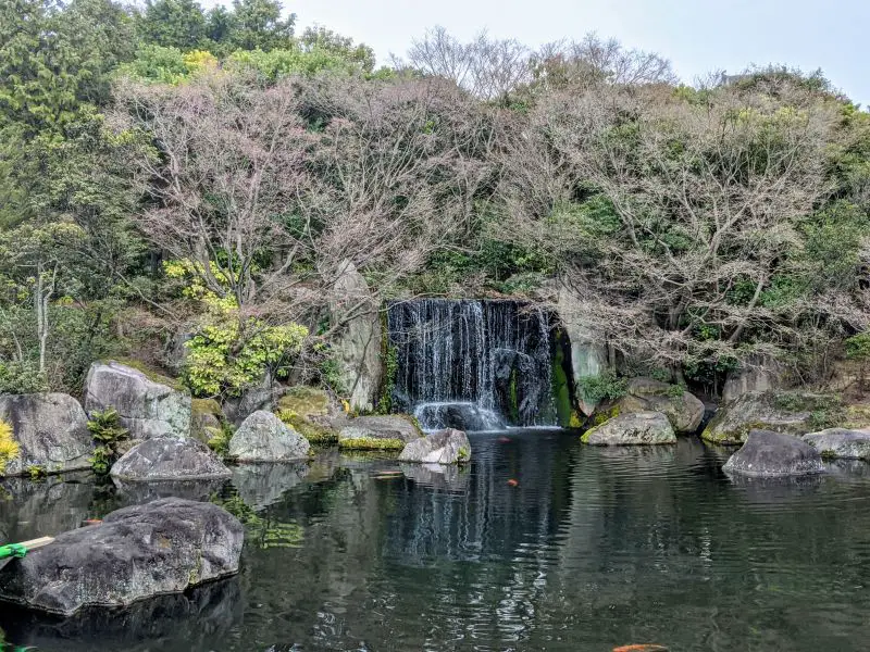 A small waterfall surrounded by trees and plants in Koko-en Garden, Himeji, Japan