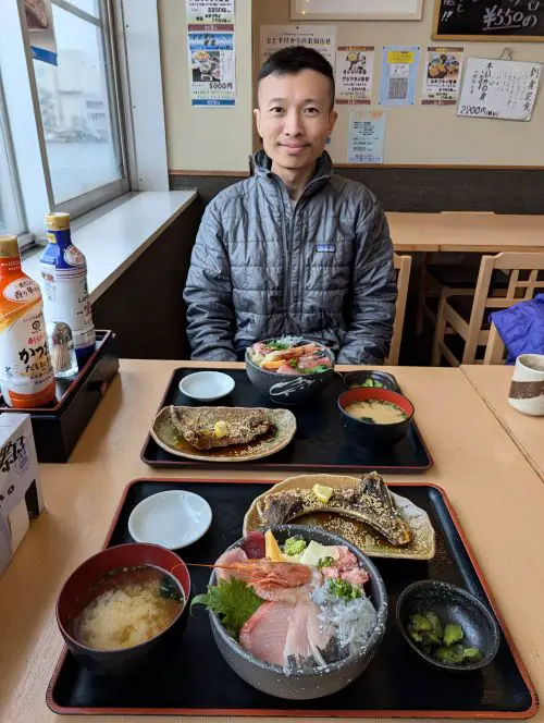Justin Huynh, Life Of Doing, smiles with the two seafood rice bowls, miso soup, fish jaw, and pickles at Shimizu Fish Market's Totosuke restaurant