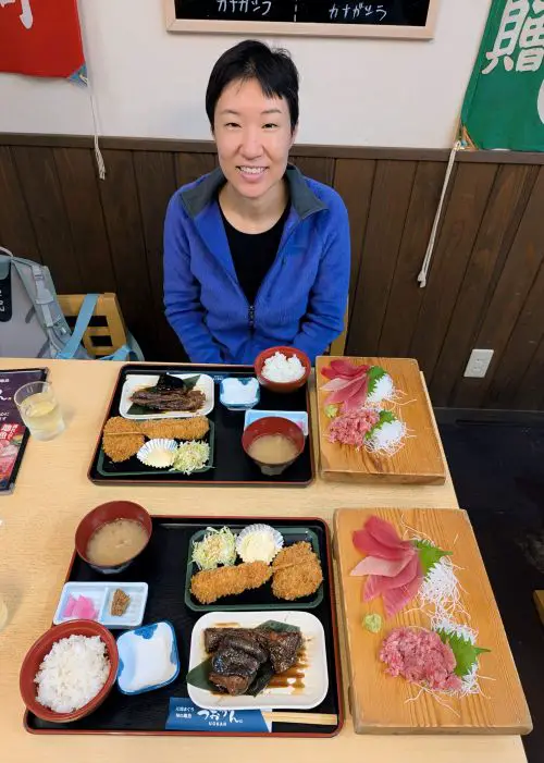 Jackie Szeto, Life Of Doing, poses with the two tuna meals which has braised tuna, tuna sushi, tuna croquette, and miso soup at Uokan, Shimizu Fish Market
