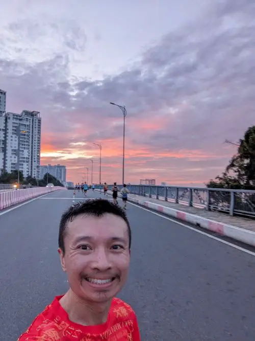 Justin Huynh, Life Of Doing, takes a selfie with the orange and pink sunrise during the Garmin Run Vietnam half marathon race