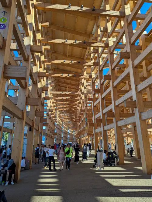 People walking under the Osaka Expo's Grand Ring wooden construction