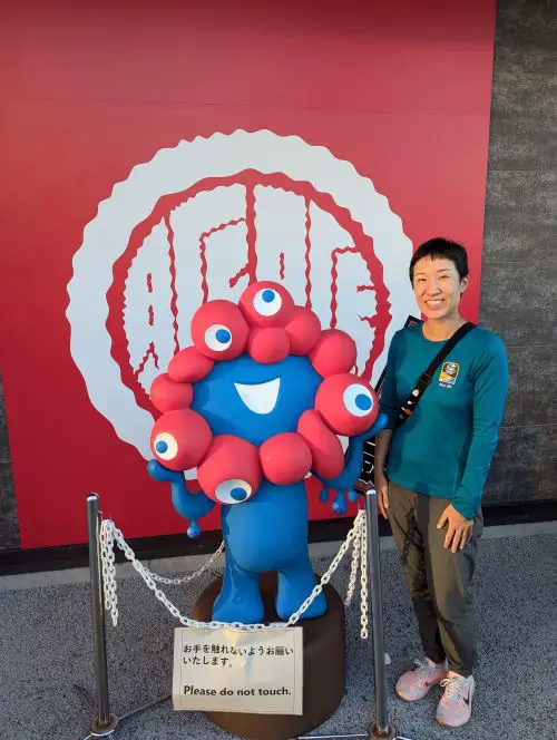 Jackie Szeto, Life Of Doing, stands next to a Myaku Myaku statue at the Osaka Expo