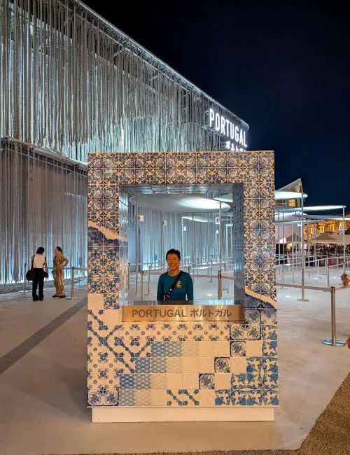 Jackie Szeto, Life Of Doing, stands in a ceramic photo frame in front of the Portugal Pavilion