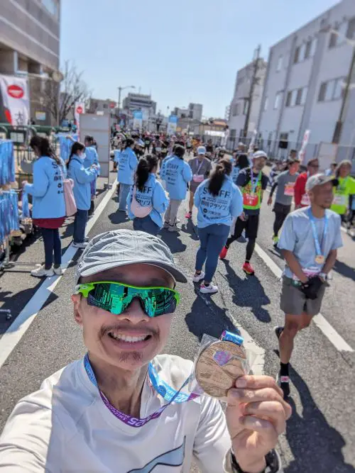 Justin Huynh, Life Of Doing, takes a selfie at the finish line and holds his finisher's medal