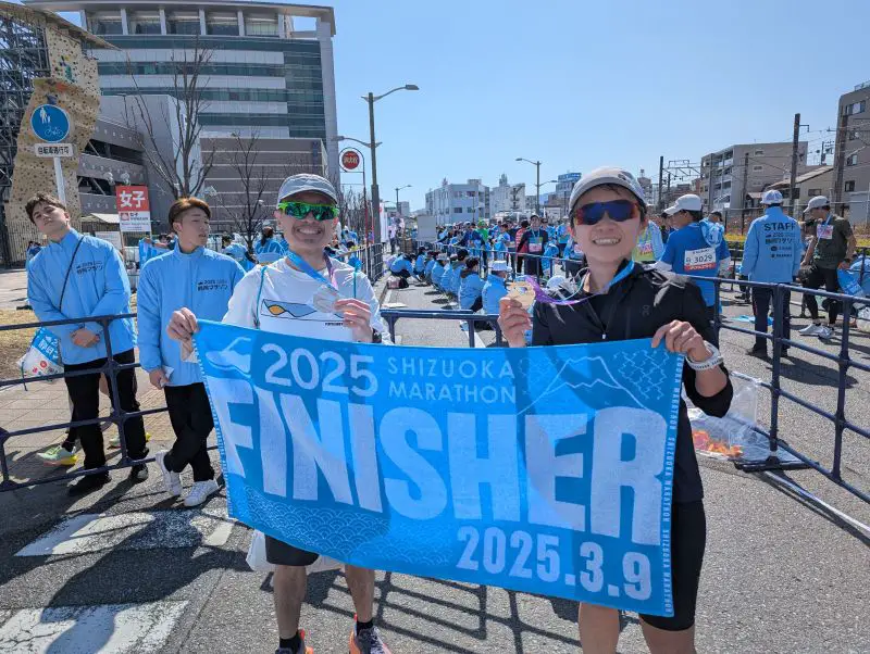 Justin Huynh, Life Of Doing, and a friend hold their finisher medals and the finisher towel at Shizuoka Marathon