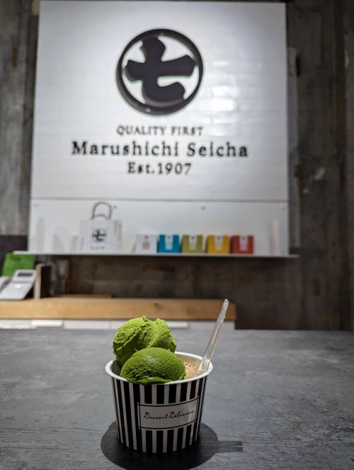 A paper cup holding three scoops of gelato: two matcha and one hojicha (roasted tea) at Nanaya Shizuoka
