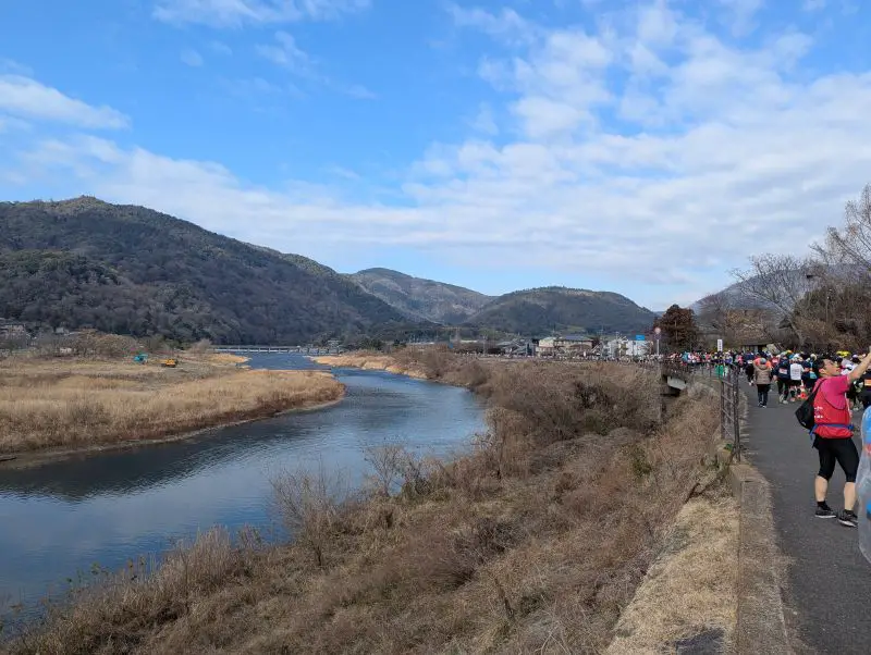 Kyoto Marathon runners run along a canal in Arashiyama area