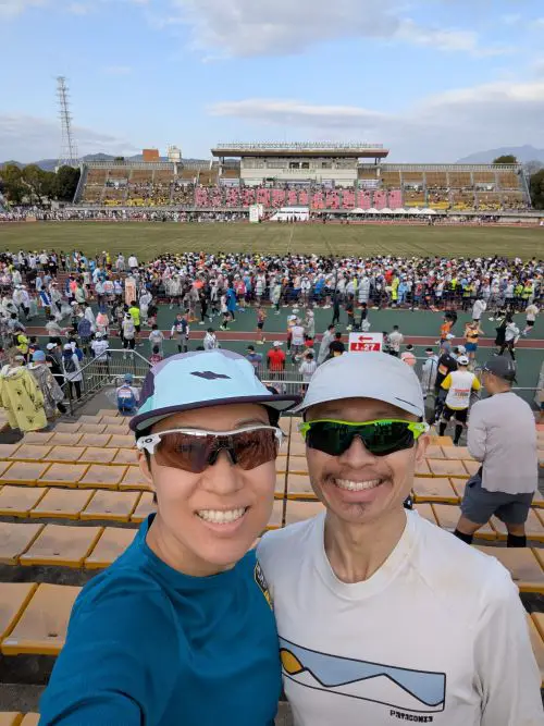 Jackie Szeto and Justin Huynh, Life Of Doing, stand in the seating area of Kyoto's Takebishi Stadium which is the start line of the Kyoto Marathon